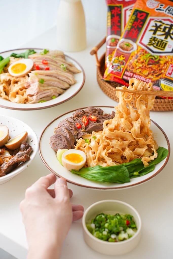 一盤四川麻辣水煮牛風味乾拌麵，充分拌勻醬汁的波浪麵上擺著燉煮的牛肉塊，與川燙的翠綠青江菜，最上面則是半顆新鮮的水煮蛋。