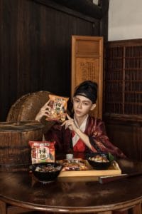 穿著古裝的男子前面桌上放著乾拌麵