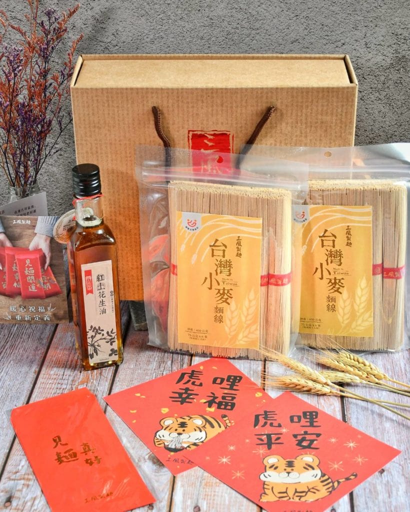 小麥麵線與花生油擺桌上，旁邊放著紅包、春聯與小麥。